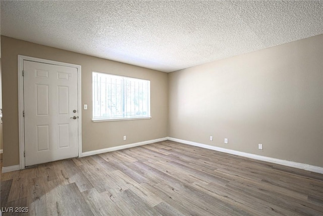 spare room featuring a textured ceiling and light hardwood / wood-style flooring