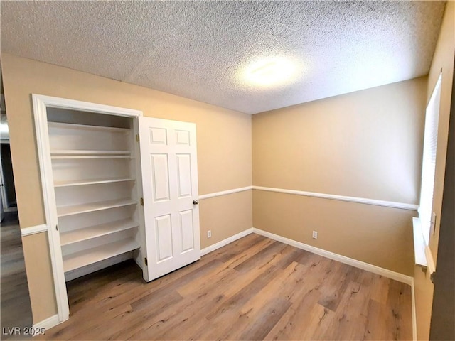 unfurnished bedroom with a closet, hardwood / wood-style floors, and a textured ceiling