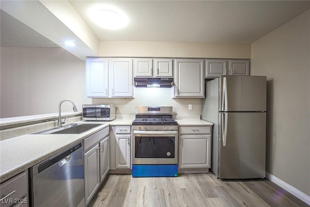 kitchen featuring gray cabinets, sink, light wood-type flooring, and appliances with stainless steel finishes