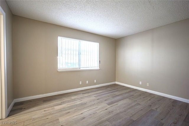 empty room with a textured ceiling and light hardwood / wood-style floors