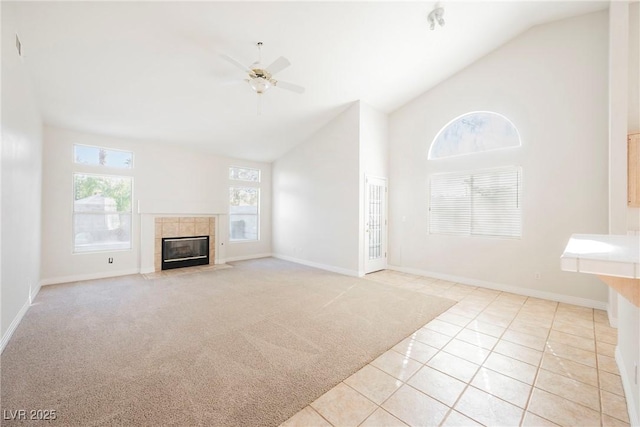 unfurnished living room with high vaulted ceiling, a tile fireplace, ceiling fan, and light tile patterned flooring