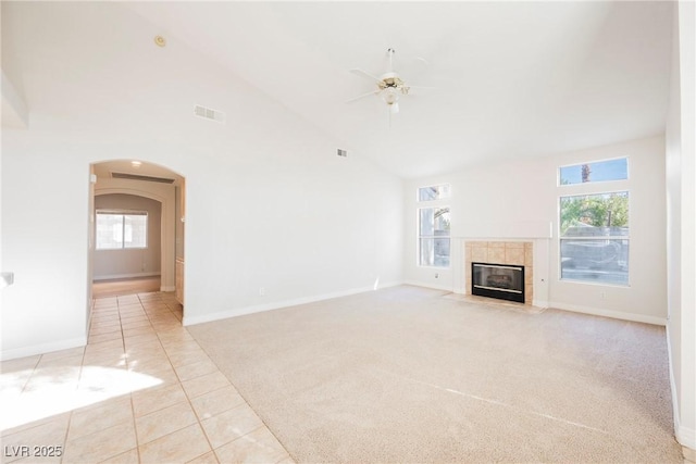 unfurnished living room with high vaulted ceiling, light tile patterned floors, a wealth of natural light, ceiling fan, and a fireplace