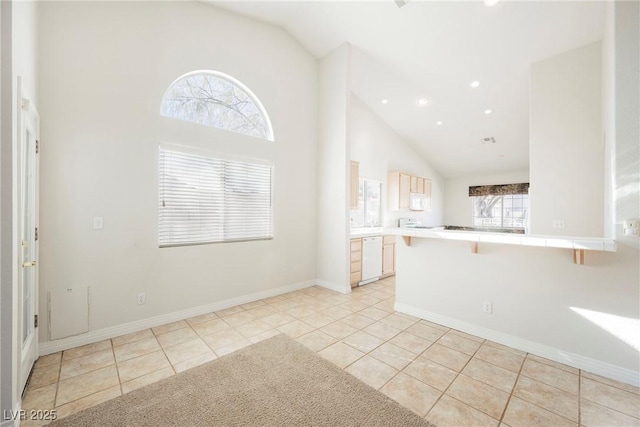 kitchen featuring a kitchen breakfast bar, kitchen peninsula, dishwasher, and light tile patterned flooring