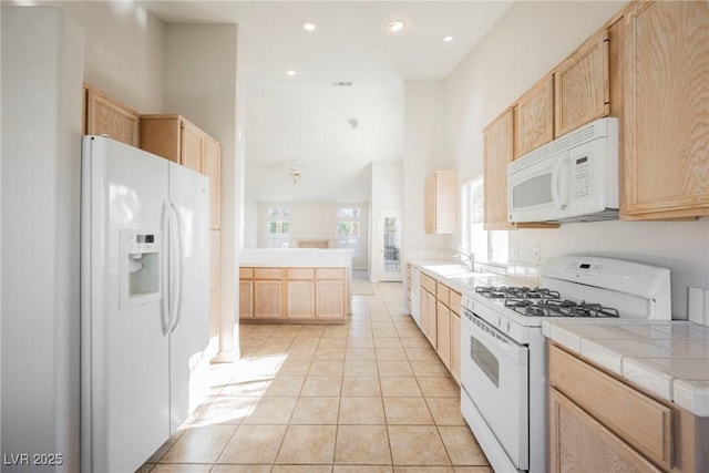 kitchen with tile counters, light brown cabinetry, and white appliances