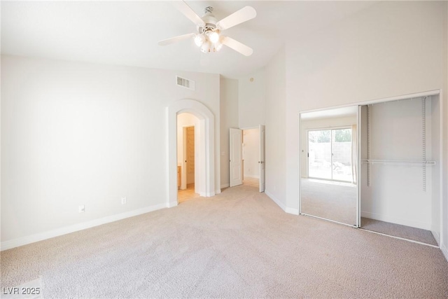 unfurnished bedroom with light carpet, lofted ceiling, a closet, and ceiling fan