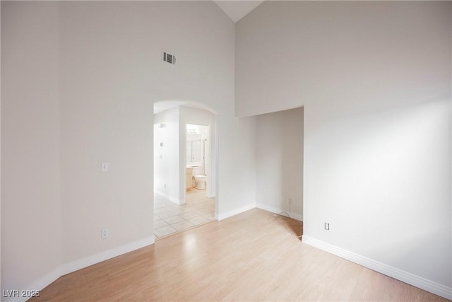 spare room featuring high vaulted ceiling and light hardwood / wood-style flooring