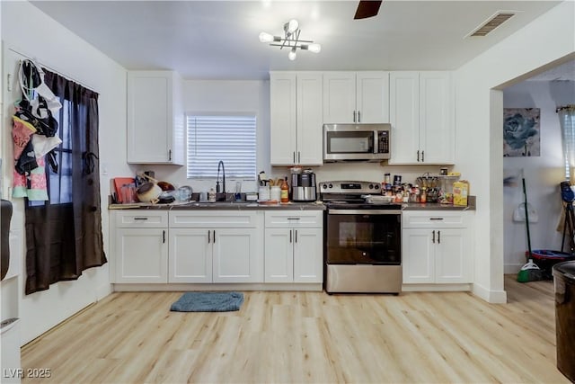 kitchen with white cabinets, stainless steel appliances, light hardwood / wood-style floors, and sink