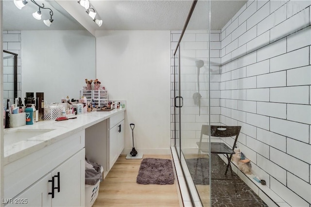 bathroom featuring hardwood / wood-style flooring, vanity, a textured ceiling, and walk in shower