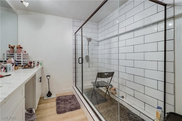 bathroom featuring vanity, a textured ceiling, hardwood / wood-style flooring, and an enclosed shower