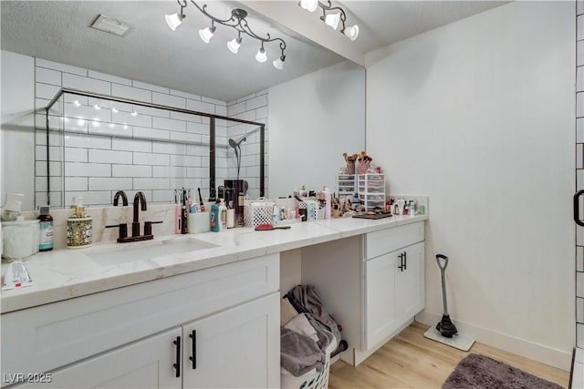 bathroom with wood-type flooring, vanity, and a shower with door