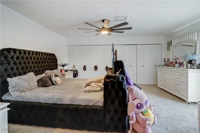 bedroom featuring a textured ceiling, light colored carpet, and ceiling fan