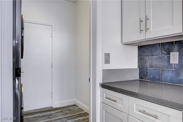 kitchen with decorative backsplash, white cabinetry, dark wood-type flooring, and dark stone counters