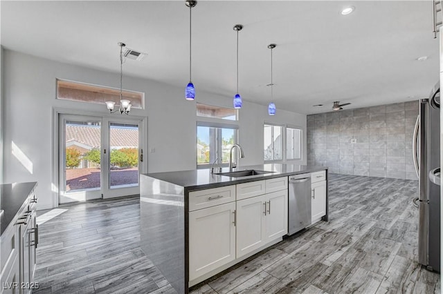 kitchen with white cabinetry, sink, stainless steel appliances, hanging light fixtures, and tile walls