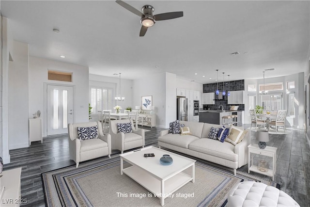 living room featuring dark hardwood / wood-style flooring and ceiling fan with notable chandelier