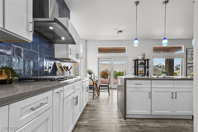 10300 Bent Brook Pl, Las Vegas, NV 89134 - kitchen with visible vents, wall chimney exhaust hood, white cabinetry, backsplash, and stainless steel gas stovetop