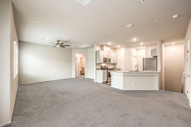 unfurnished living room featuring carpet flooring, ceiling fan, and sink