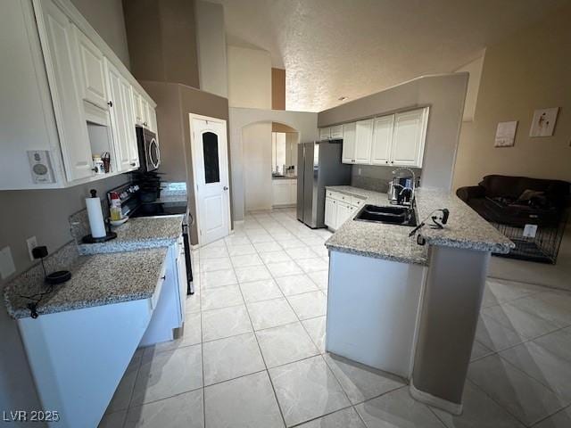 kitchen featuring white cabinetry, stainless steel appliances, light stone counters, kitchen peninsula, and light tile patterned floors