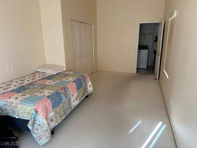 carpeted bedroom with a closet and washer / dryer