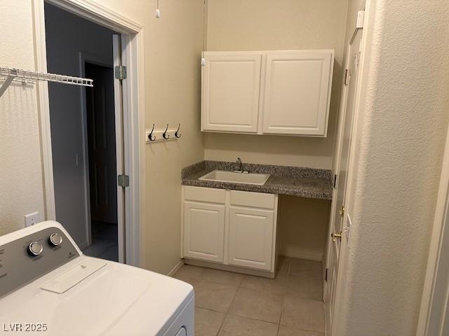 clothes washing area featuring washer / clothes dryer, sink, light tile patterned floors, and cabinets