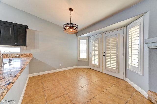 unfurnished dining area featuring a chandelier, light tile patterned floors, french doors, and sink