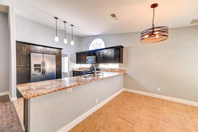 kitchen featuring light stone countertops, sink, hanging light fixtures, kitchen peninsula, and appliances with stainless steel finishes