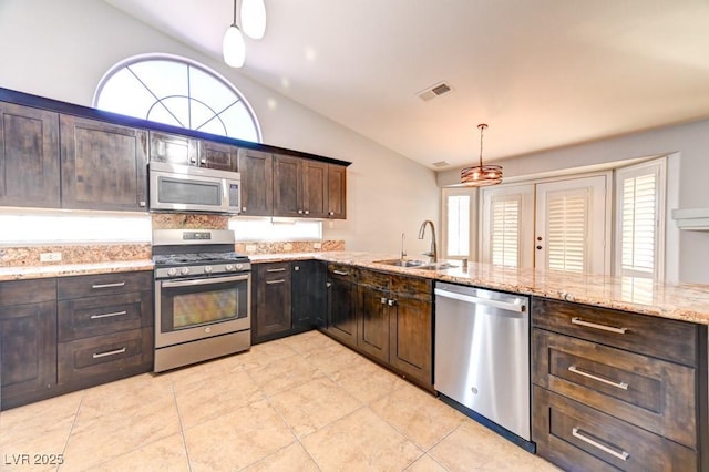 kitchen with appliances with stainless steel finishes, dark brown cabinets, sink, pendant lighting, and lofted ceiling