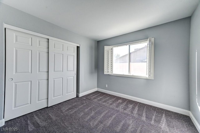 unfurnished bedroom featuring dark carpet and a closet