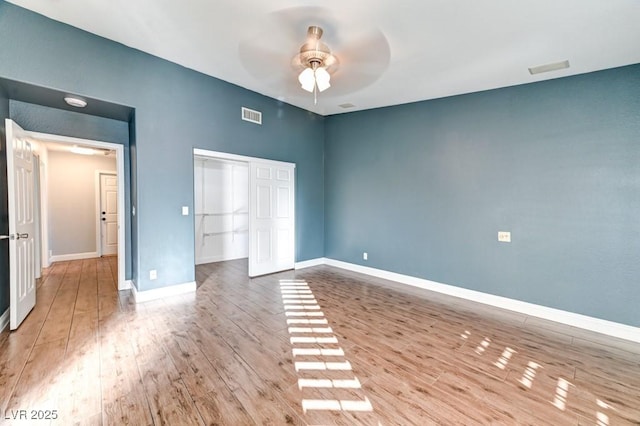 unfurnished bedroom featuring hardwood / wood-style floors, ceiling fan, and a closet