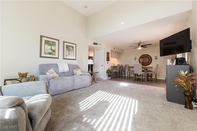 carpeted living room featuring ceiling fan and visible vents