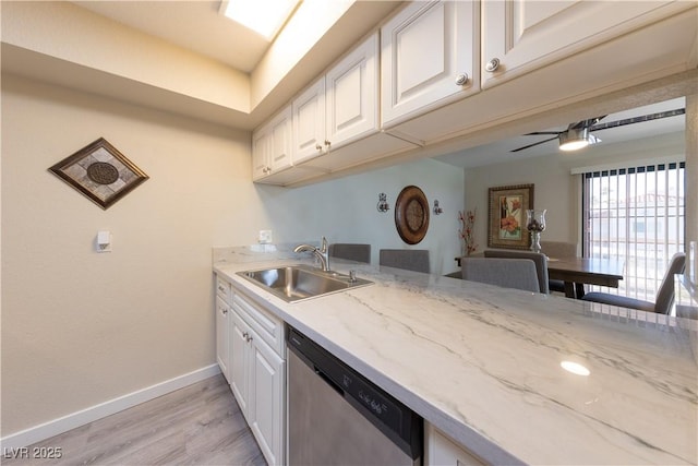 kitchen with baseboards, stainless steel dishwasher, a sink, and white cabinets