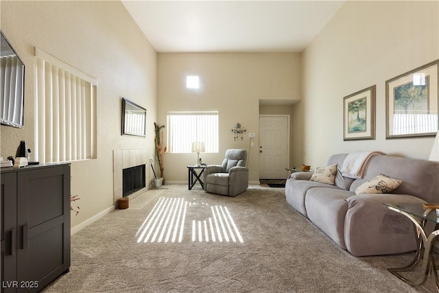 living room with light carpet, a high ceiling, baseboards, and a tile fireplace