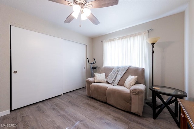 living room with a ceiling fan and light wood-style flooring