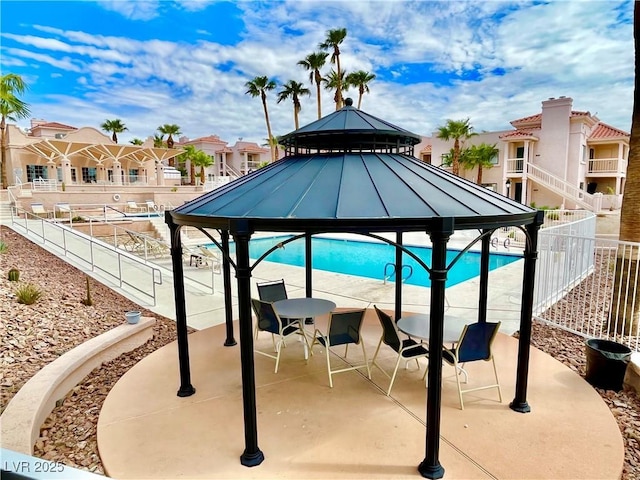 exterior space with a residential view, fence, a gazebo, a patio area, and a pool