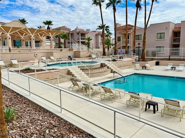 community pool with stairway, a patio area, and a residential view