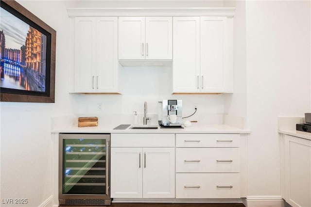 bar featuring white cabinets, beverage cooler, and sink