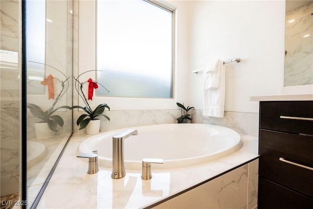 bathroom with tiled bath and vanity