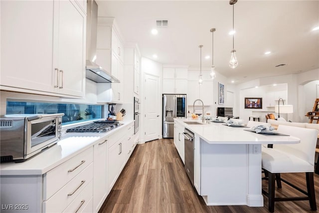 kitchen featuring stainless steel appliances, white cabinetry, and hanging light fixtures