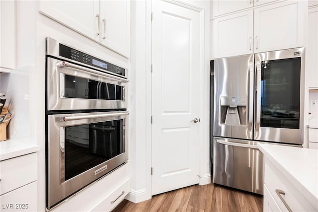 kitchen with white cabinets, light hardwood / wood-style flooring, and appliances with stainless steel finishes