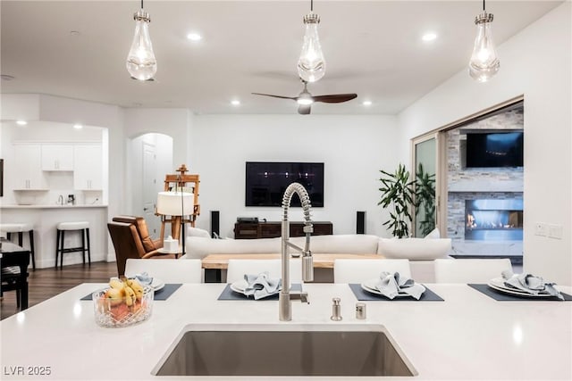 kitchen featuring sink, ceiling fan, decorative light fixtures, and wood-type flooring