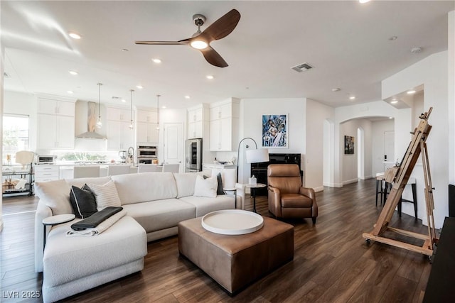 living room featuring ceiling fan and dark hardwood / wood-style flooring