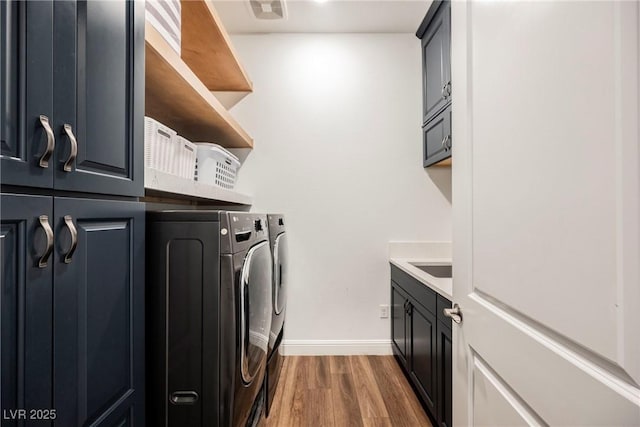 laundry room with washer and dryer, dark hardwood / wood-style flooring, cabinets, and sink