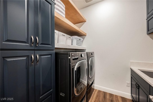 laundry area with washer and dryer, dark hardwood / wood-style flooring, and cabinets