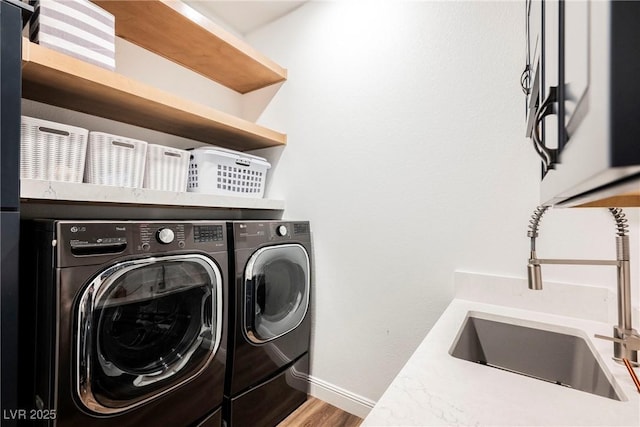 washroom featuring washing machine and dryer, wood-type flooring, and sink