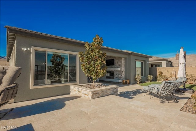 back of house featuring exterior fireplace and a patio area