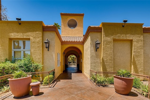 view of exterior entry with a tile roof and stucco siding