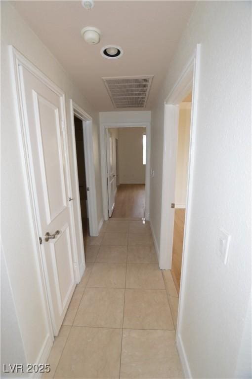 hall featuring light tile patterned floors, visible vents, and baseboards