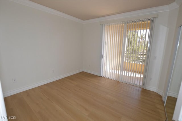 spare room featuring baseboards, light wood finished floors, and crown molding