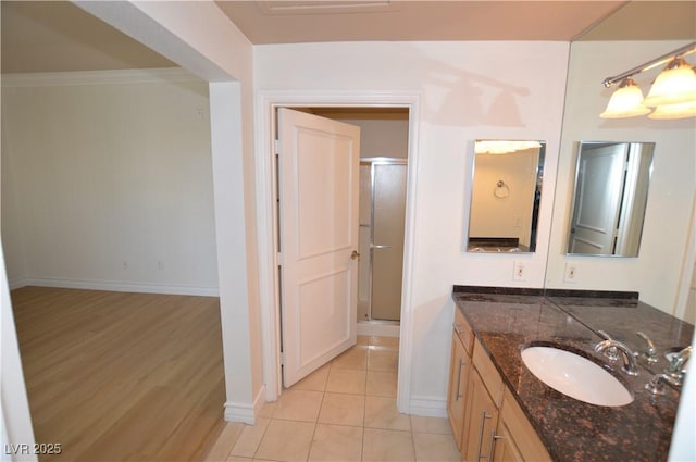 bathroom featuring baseboards, vanity, a shower stall, and tile patterned floors