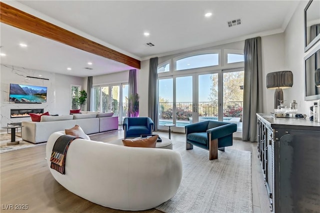 living room featuring a fireplace, light wood-type flooring, and beamed ceiling