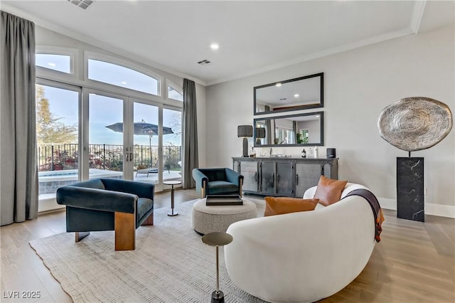 living room with light hardwood / wood-style floors, ornamental molding, and indoor bar